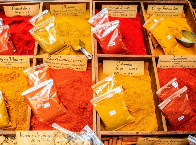 A vibrant display of various spices in a market, showcasing colorful powders like curry and paprika.